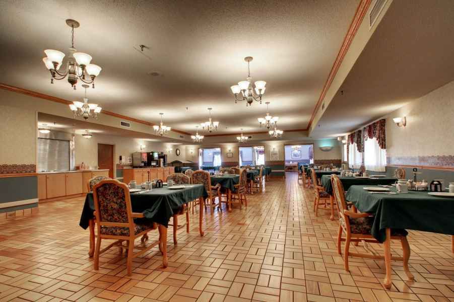 A spacious restaurant dining area with neatly arranged tables and elegant chandeliers.