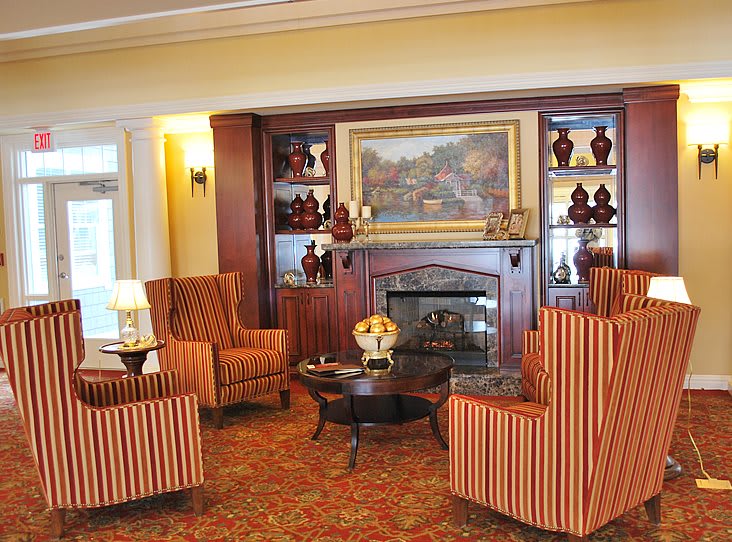 A cozy living room with a fireplace, decorated in a traditional style with striped armchairs.