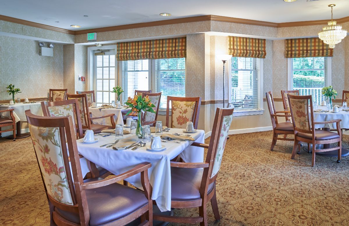 An elegantly decorated dining room with neatly arranged tables and chairs, featuring large windows and soft lighting.