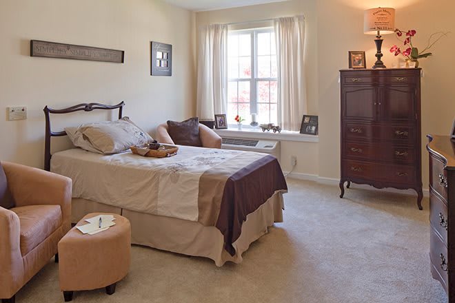 A cozy bedroom with a bed, window with curtains, and classic furniture.