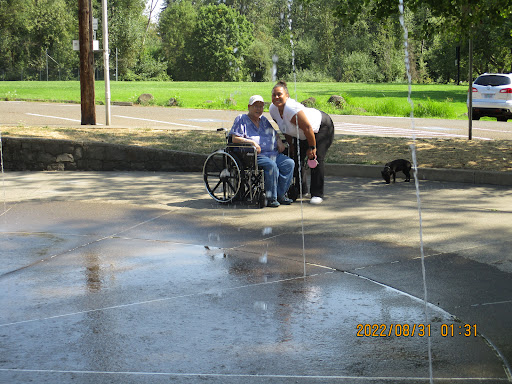 A joyful moment shared outdoors as two individuals enjoy a sunny day near a splash of water.