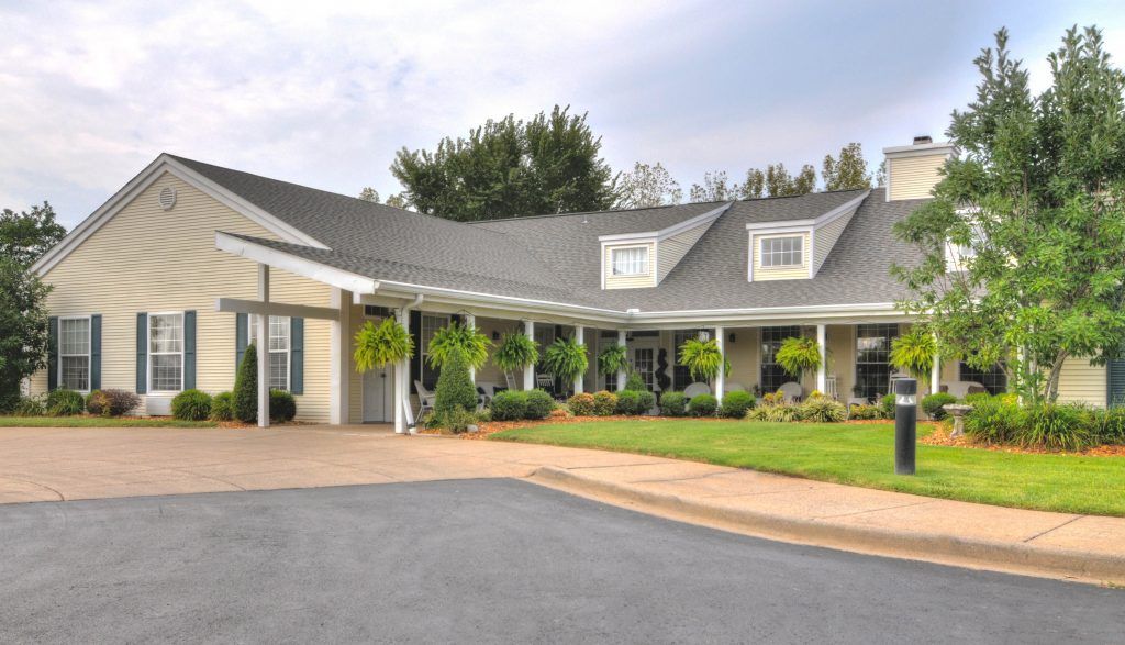 A spacious house with a large porch and well-maintained landscaping.