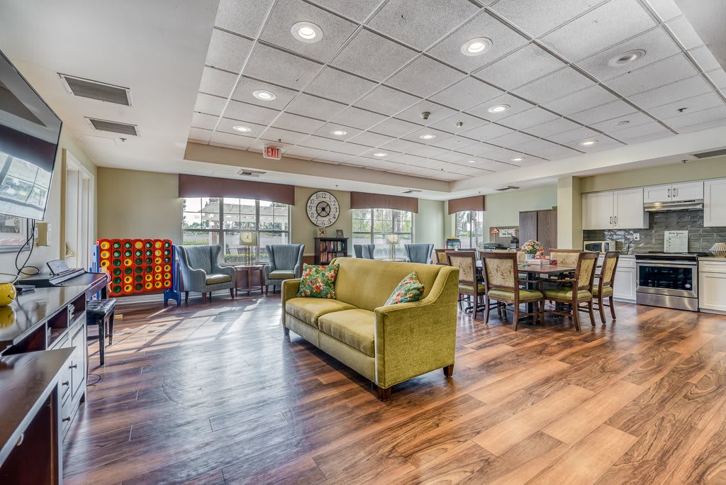 A spacious, well-lit interior with a green sofa and dining tables on hardwood floors.