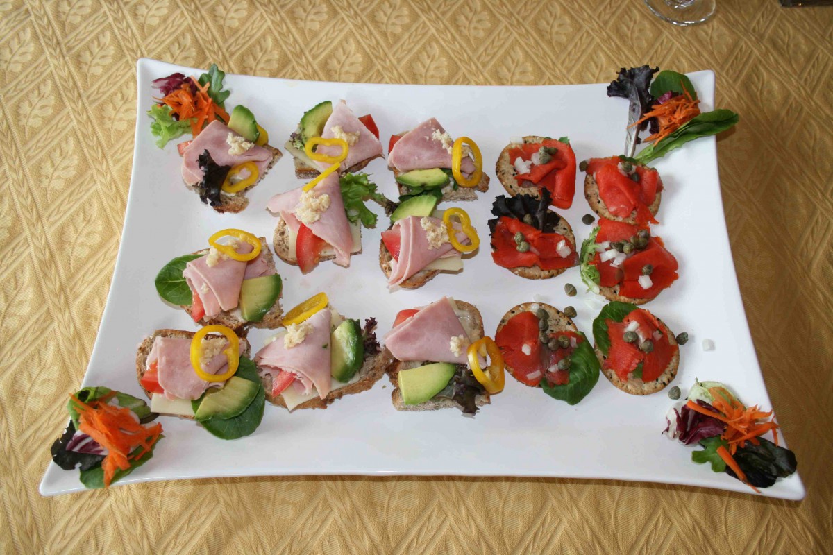 A platter of assorted sandwiches featuring ham, vegetables, and garnishes.