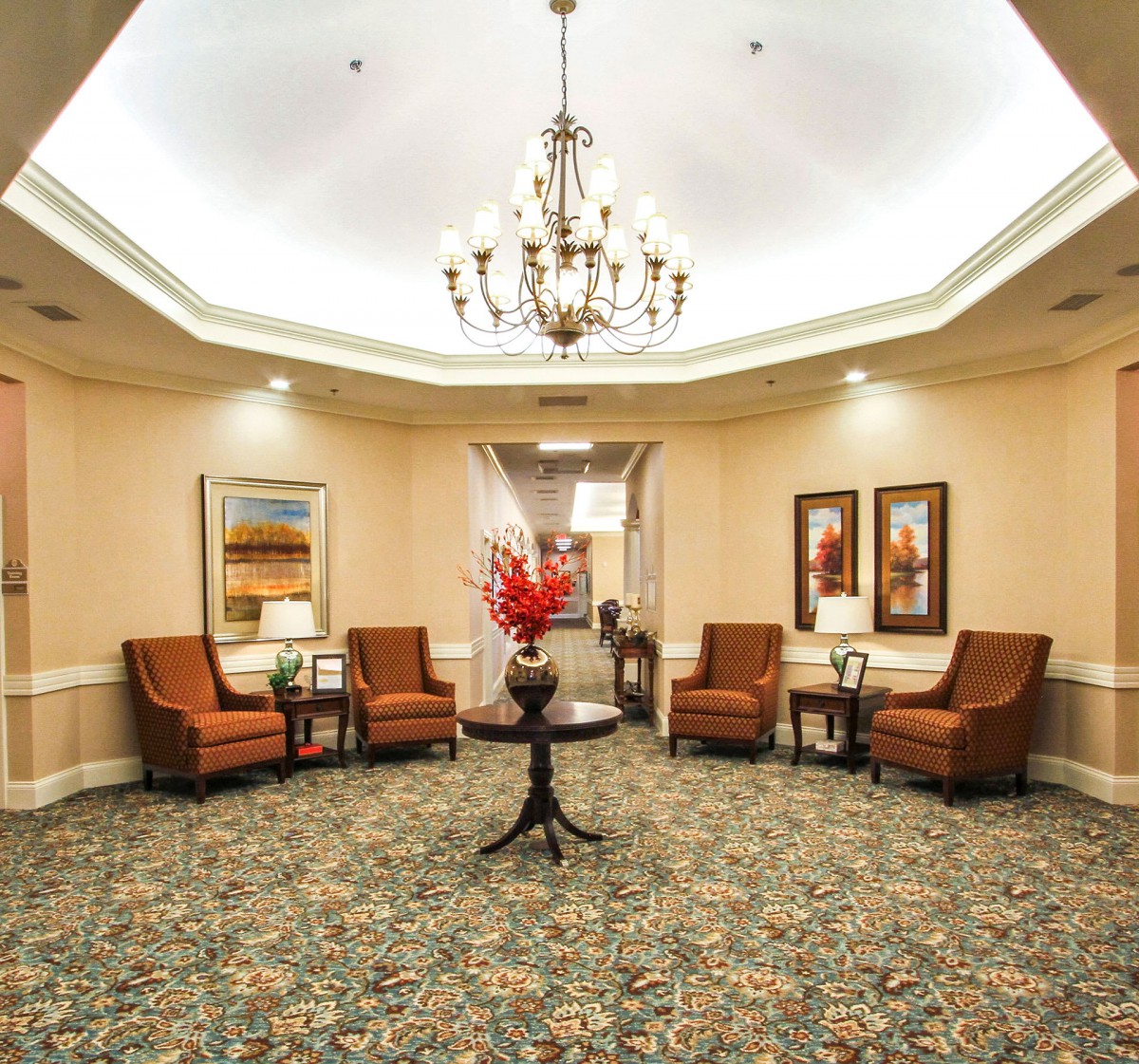 A well-decorated lobby with elegant furnishings and a central chandelier.
