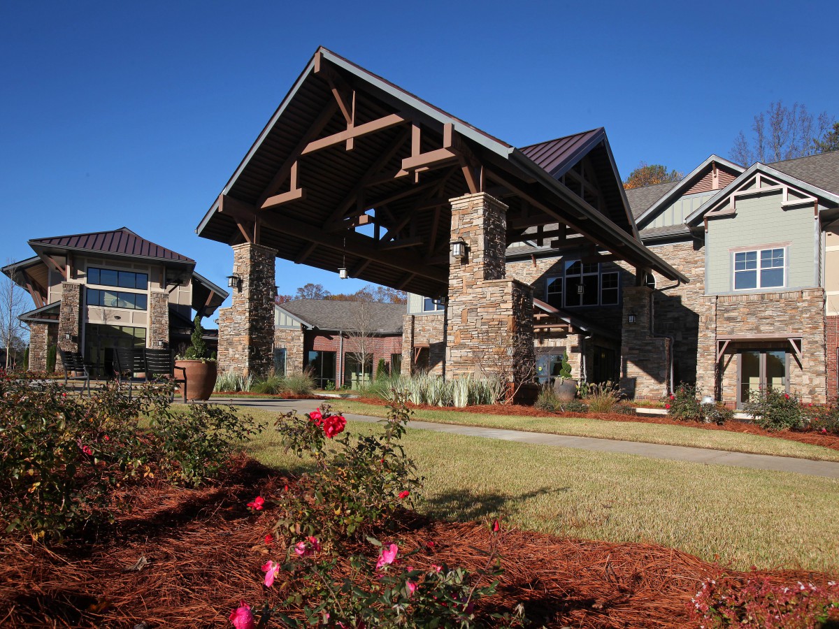 A beautiful building entrance with stone architecture and landscaped garden featuring roses.