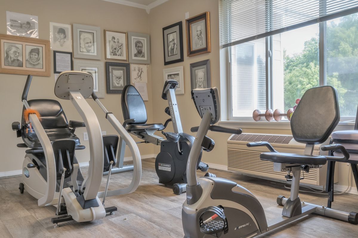 A well-equipped home gym with various exercise machines and framed pictures on the wall.