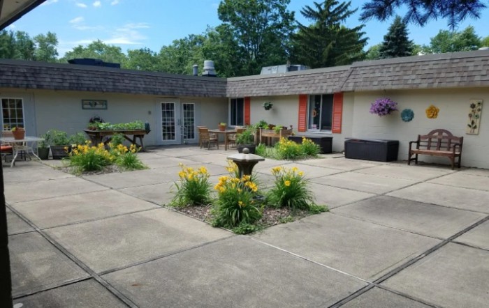 A beautiful patio area with a central fountain, surrounded by flowers and greenery.