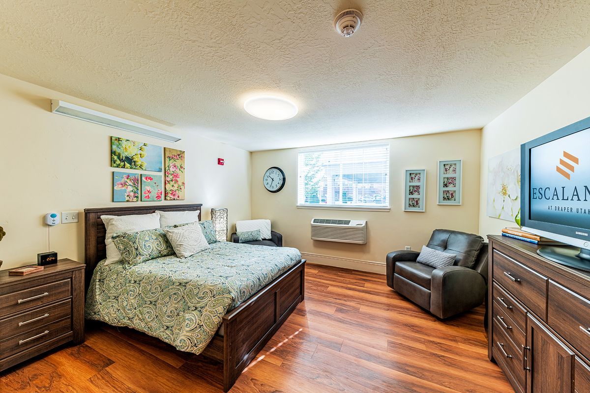 A cozy and well-decorated bedroom with a bed, armchair, and artwork on the walls.