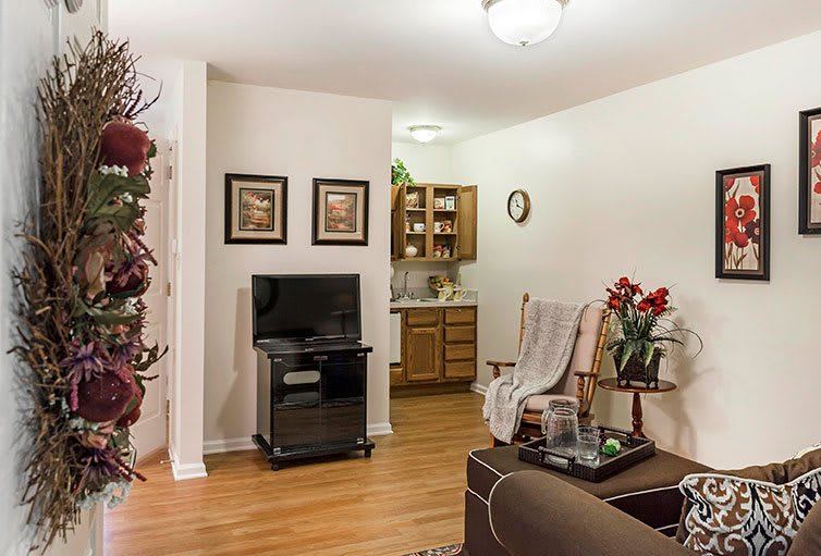 Cozy living room with a small kitchen area and classic decor.