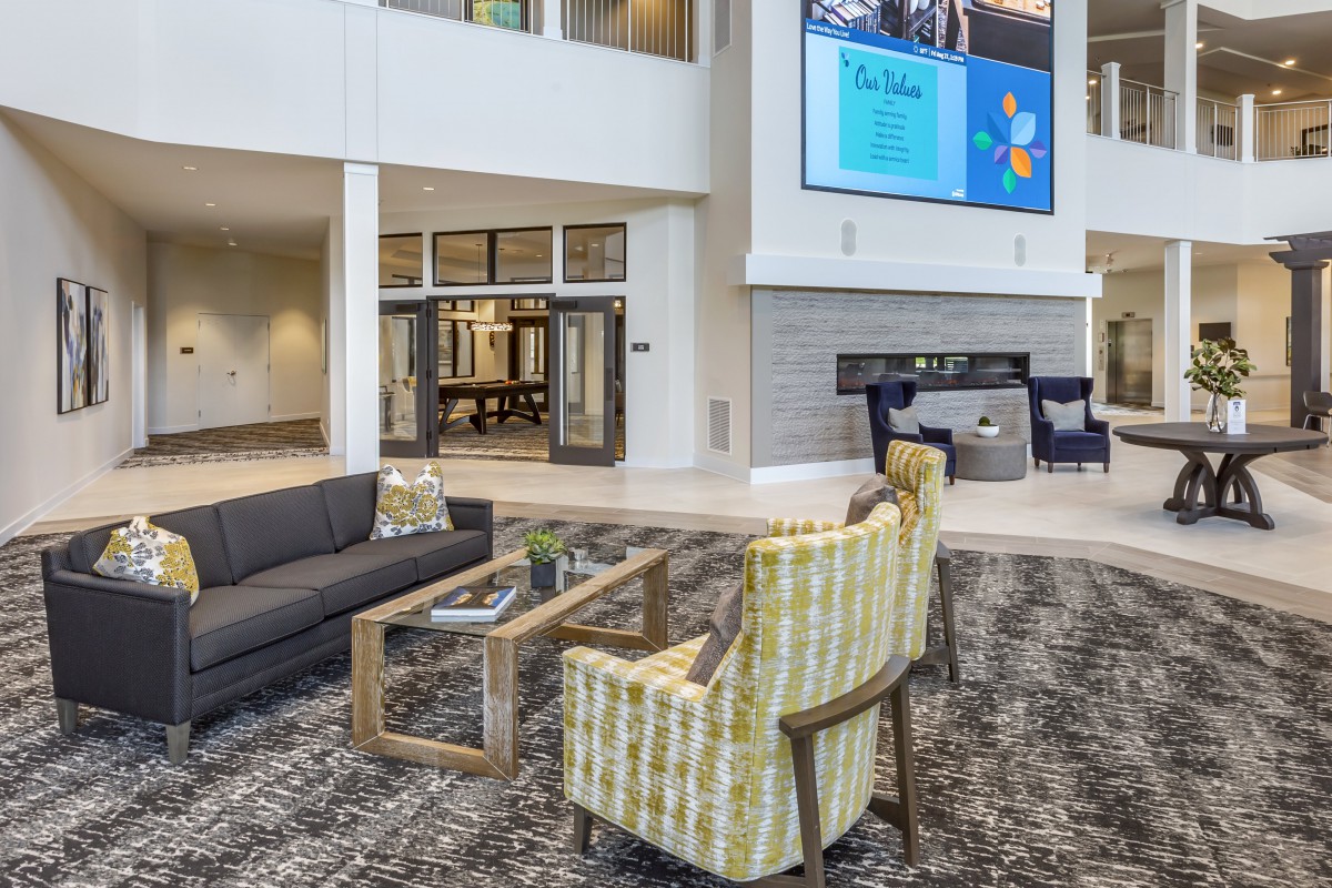 A modern lobby with comfortable seating and a fireplace, featuring a large television screen.