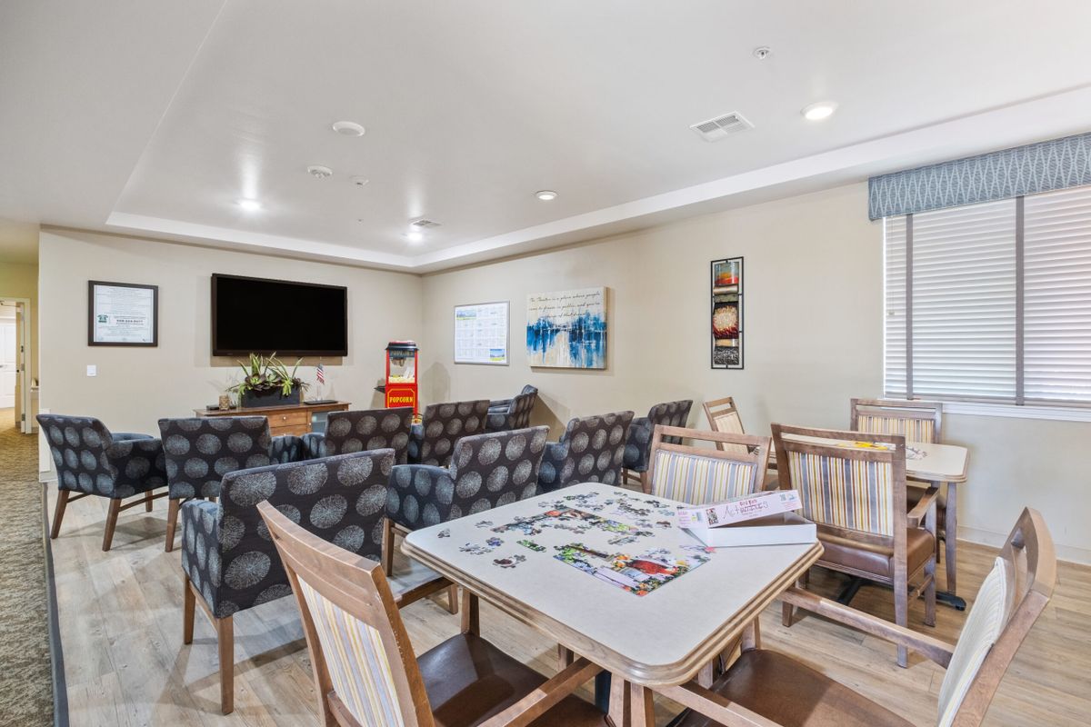 A cozy living room featuring a game table, comfortable seating, and a large television.
