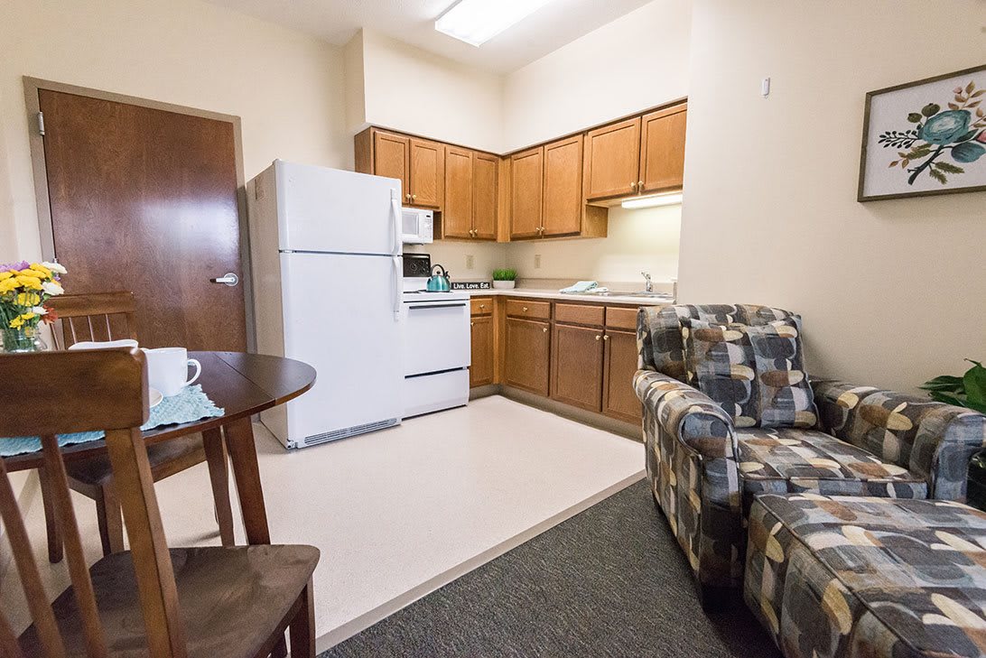 A cozy apartment kitchen and living area with wooden cabinets and a comfortable sofa.