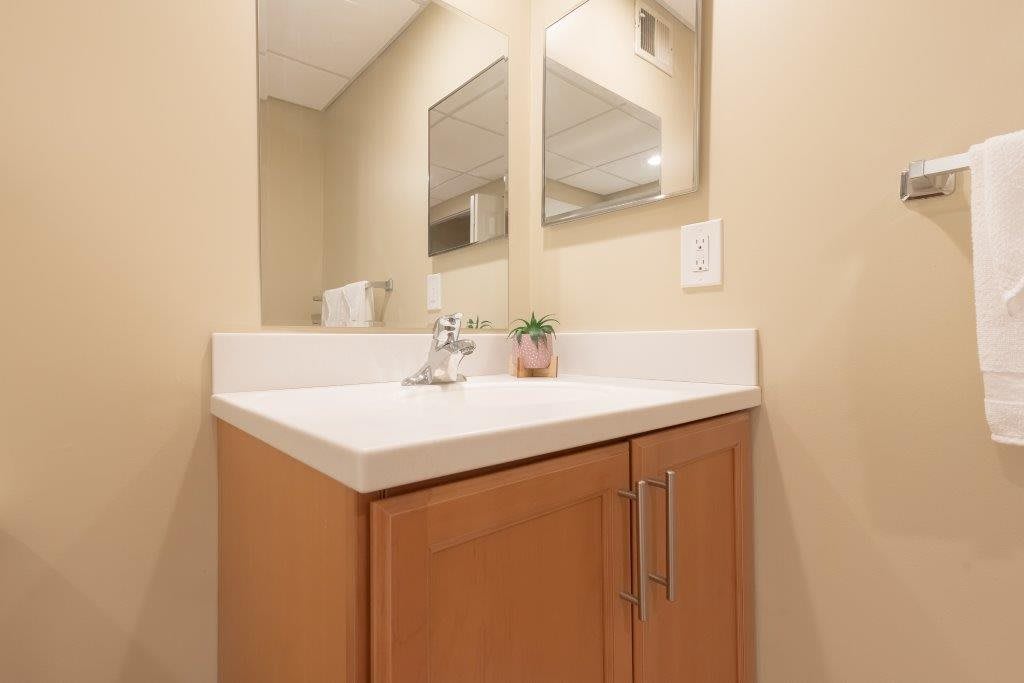 A bathroom with a modern sink and mirror above a wooden cabinet.