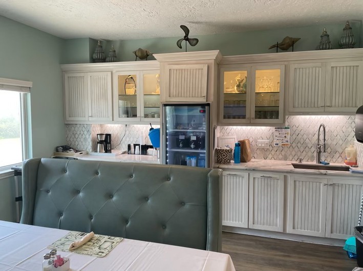 A modern kitchen with white cabinets, a refrigerator, and ambient lighting.