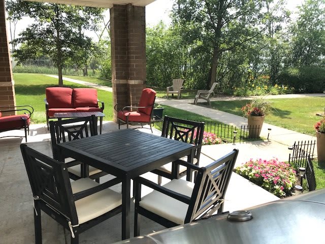 A serene patio with comfortable seating surrounded by lush greenery.