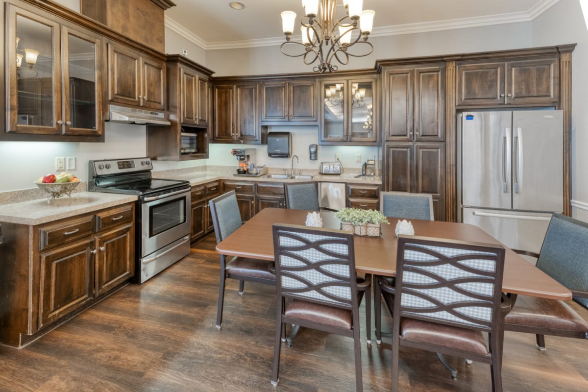 A spacious kitchen with wooden cabinets, a dining table, and modern appliances.