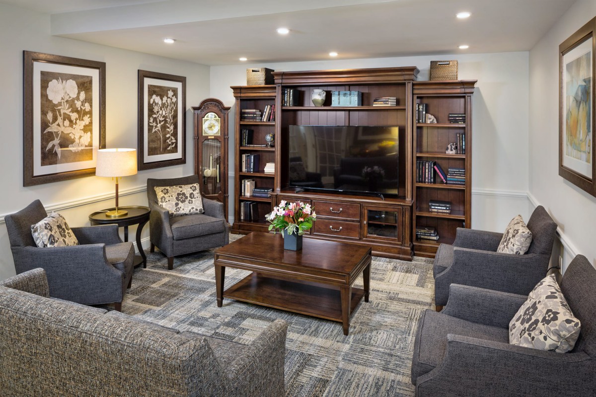 A cozy living room with comfortable seating, a large bookshelf, and a television.