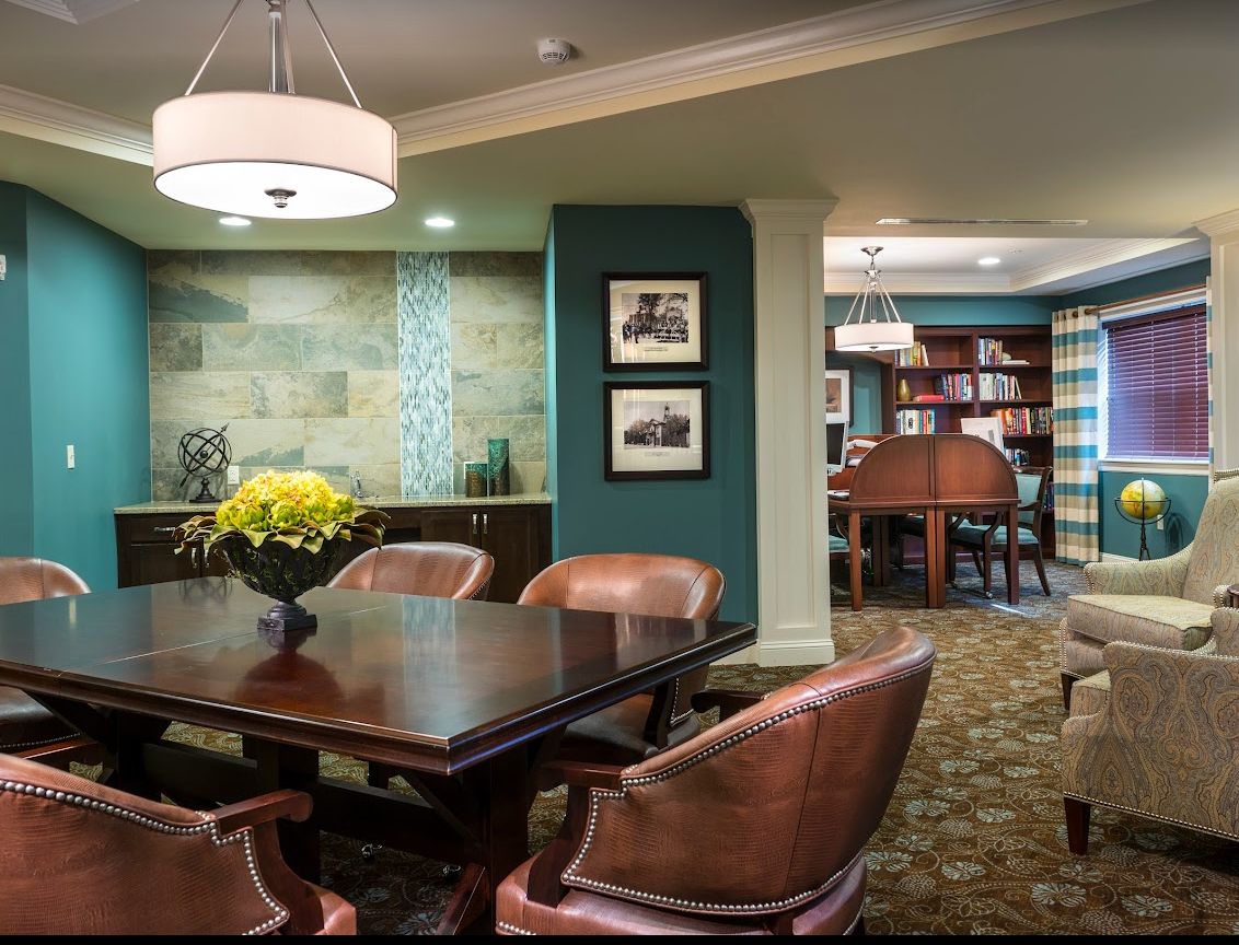 A stylish dining and reading area with a wooden table, leather chairs, and bookshelves.