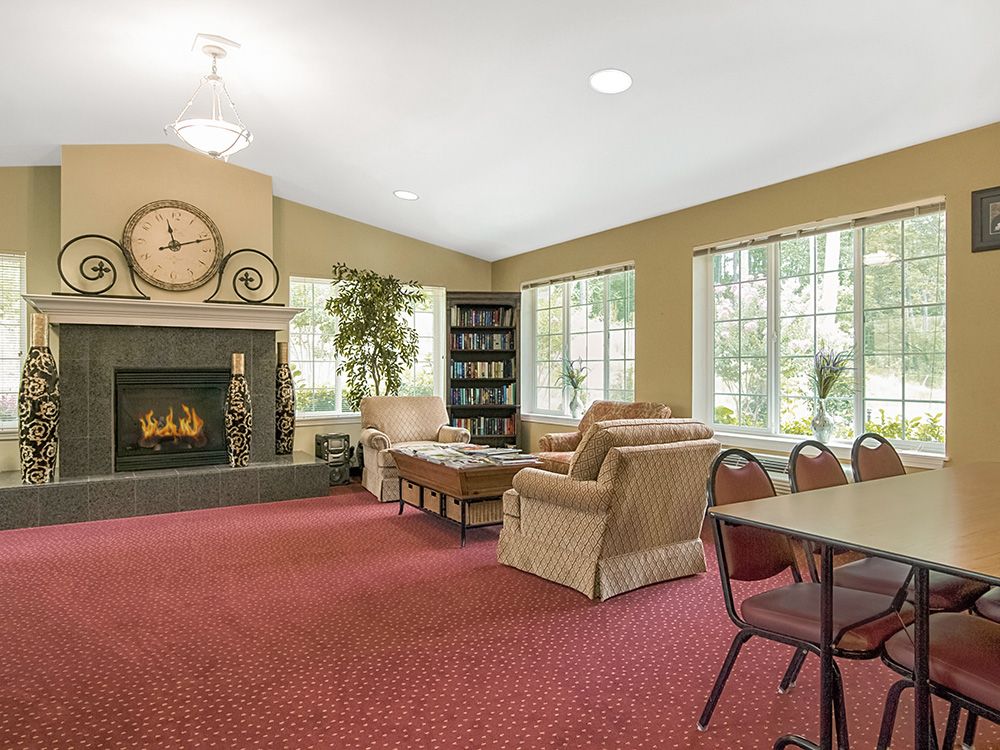 A cozy living room with a fireplace, plush furniture, and large windows.