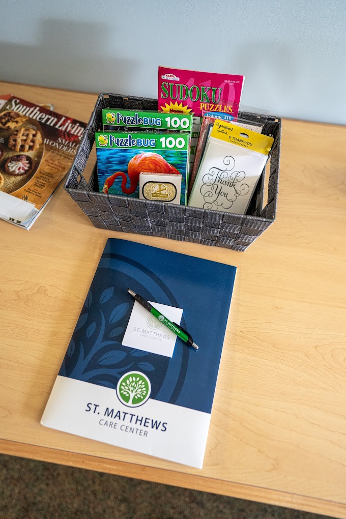 A collection of magazines, a basket containing assorted teas, and a notebook with a pen on a desk.