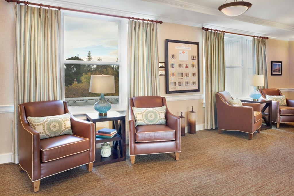A cozy living room with leather chairs, large windows, and tasteful decor.