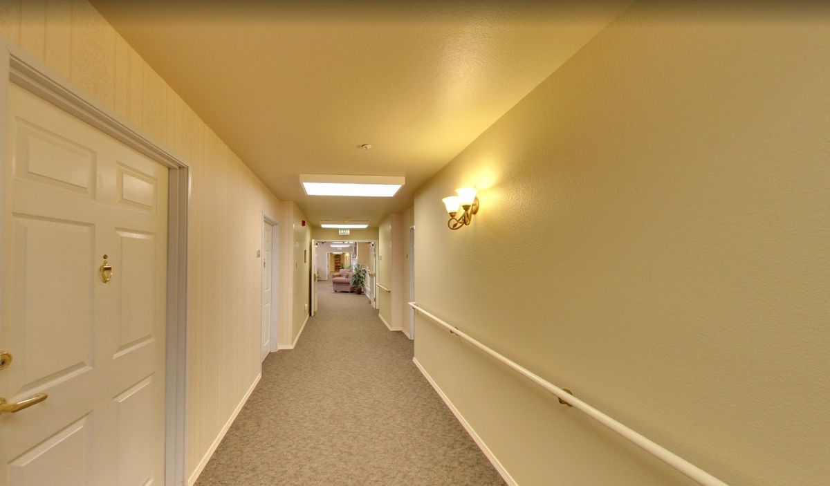 A well-lit corridor with carpeted flooring and handrails along the walls.