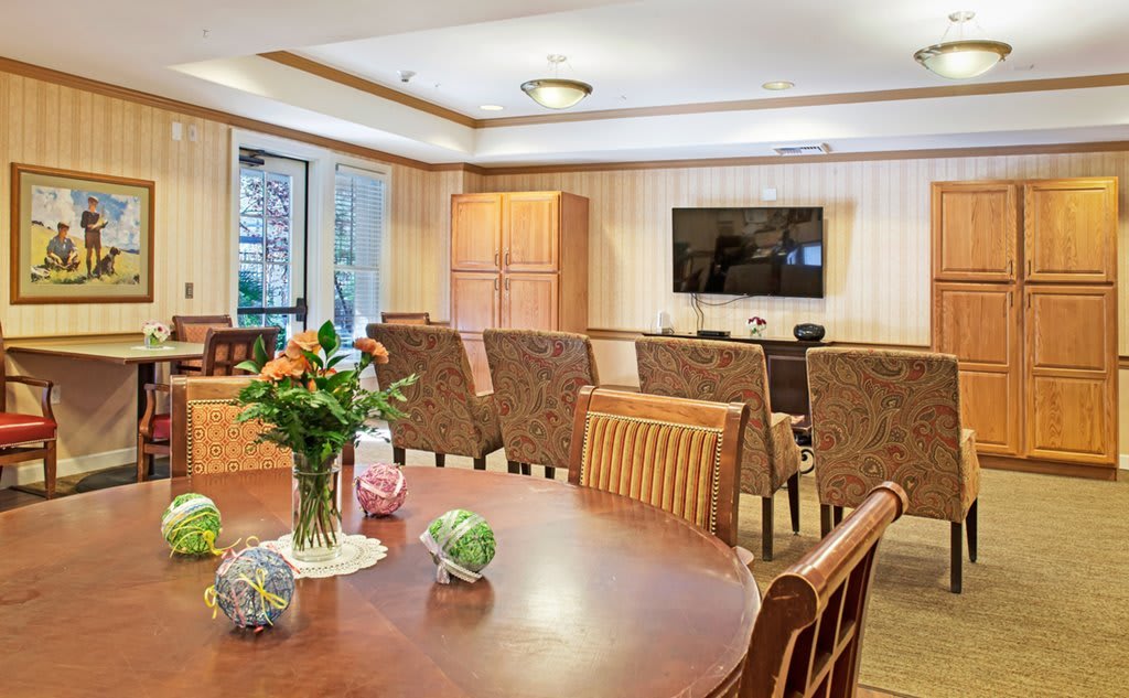 A cozy living room featuring a television, wooden furniture, and a table adorned with flowers.