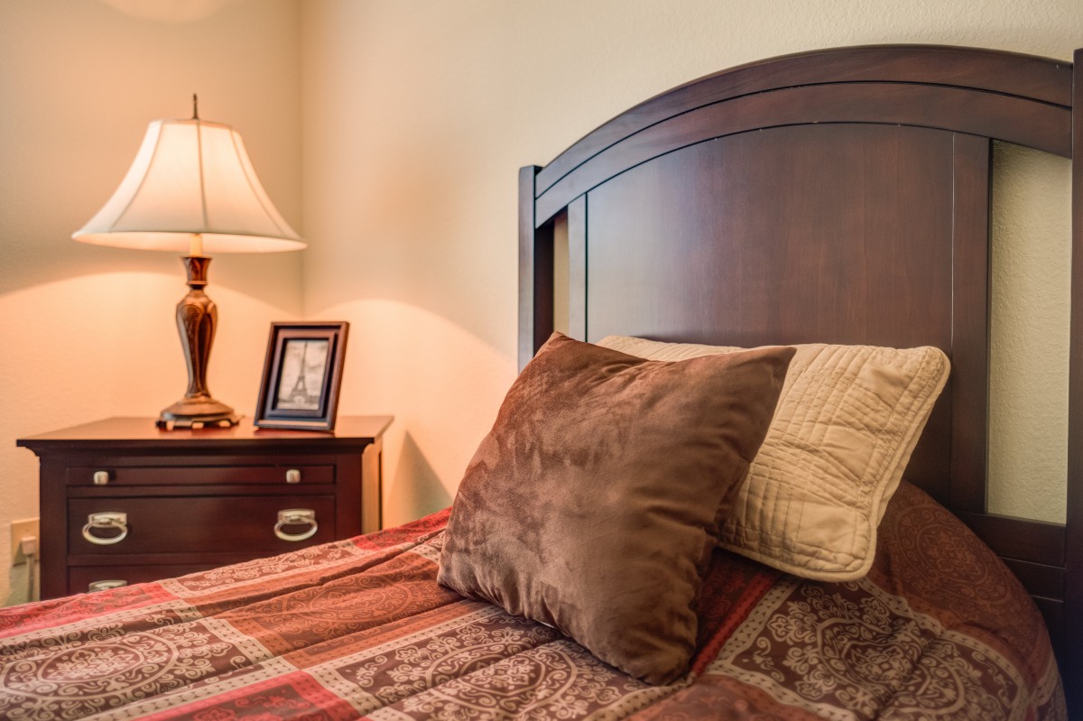 A cozy bedroom with a wooden headboard and a neatly arranged nightstand.