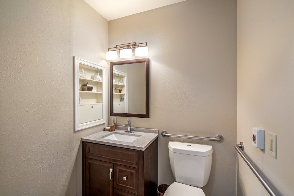 A small bathroom with a vanity, mirror, and toilet.