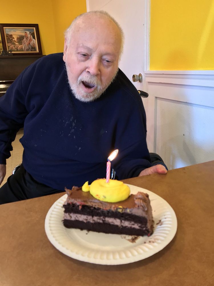 An elderly person blowing out a candle on a birthday cake.