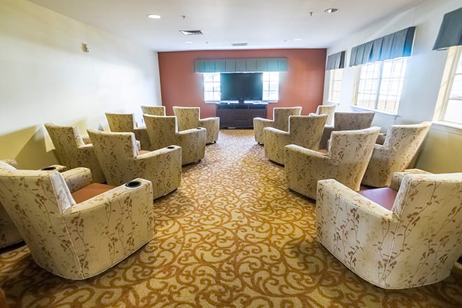 A small screening room with comfortable seating arranged in rows facing a television.