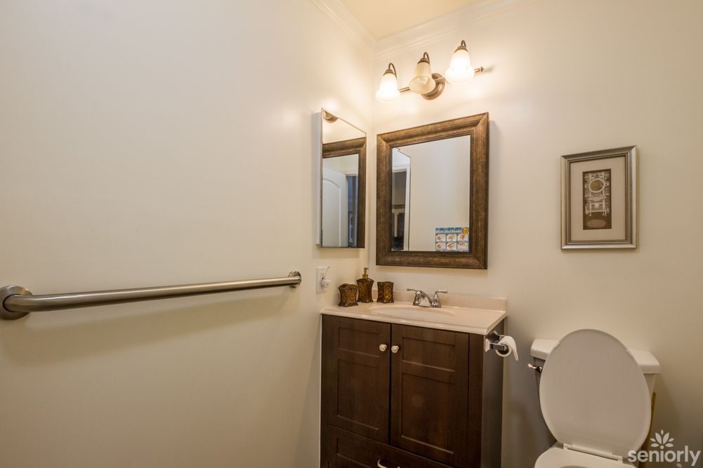 A small bathroom with a vanity, mirror, and lighting fixture.