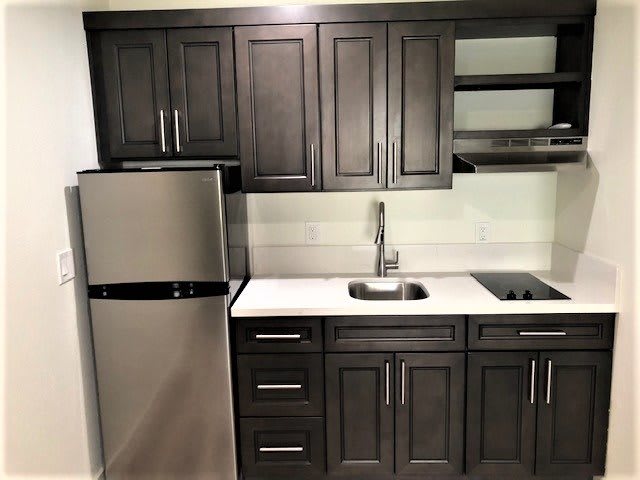 A modern kitchen with dark cabinets and stainless steel appliances.