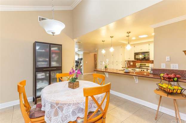 A cozy dining area with a round table and wooden chairs, adjacent to an open-concept kitchen featuring modern lighting and cabinetry.