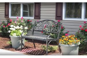 A decorative bench surrounded by colorful potted flowers in a garden setting.