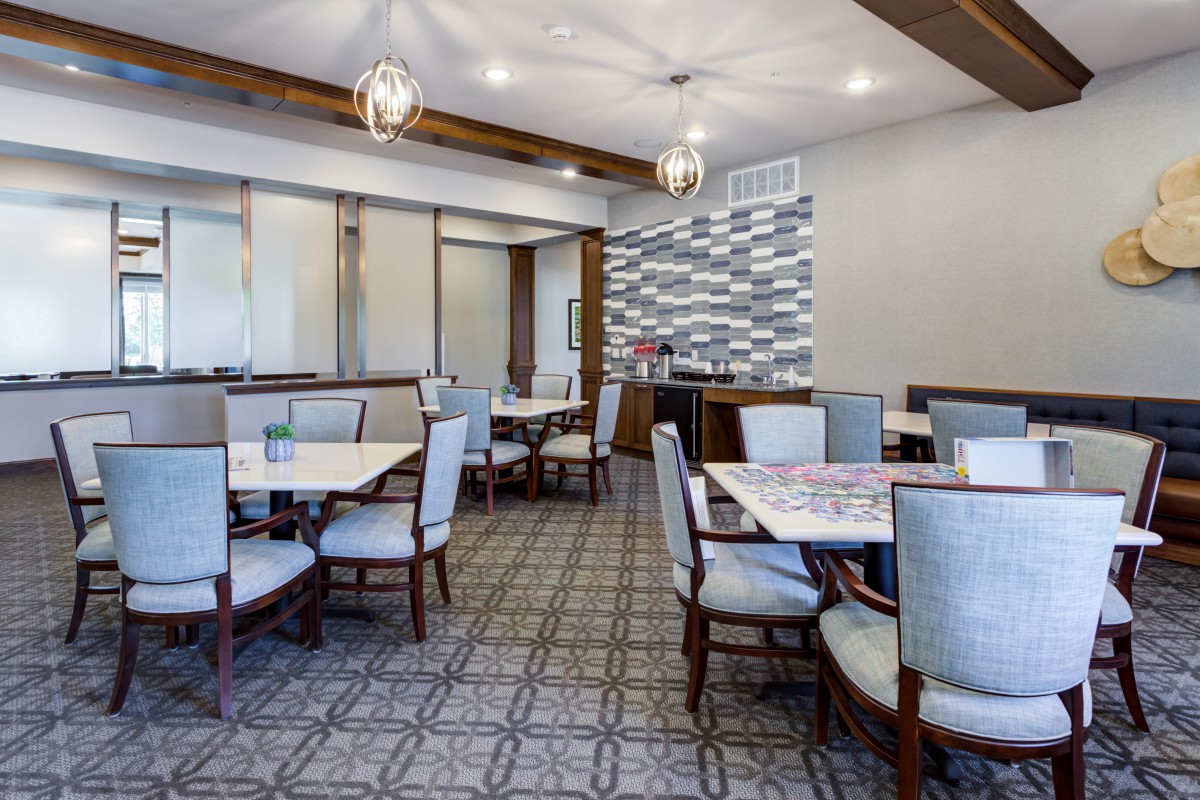 A modern dining area with neatly arranged tables and chairs, featuring stylish ceiling lights and contemporary decor.