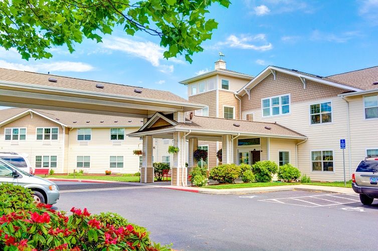 A well-maintained residential building with a landscaped entrance and a clear sky overhead.
