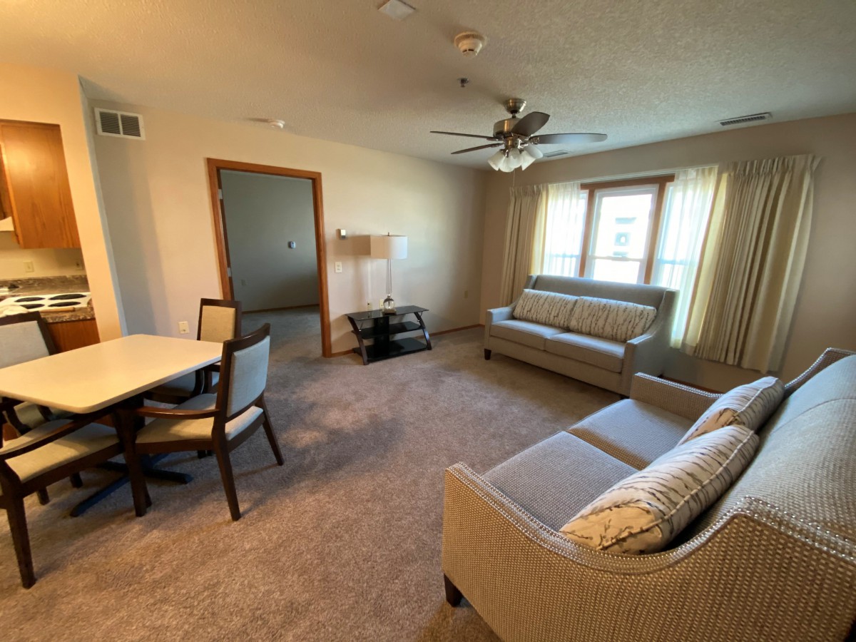 A cozy living room with a sofa, dining table, and large window.