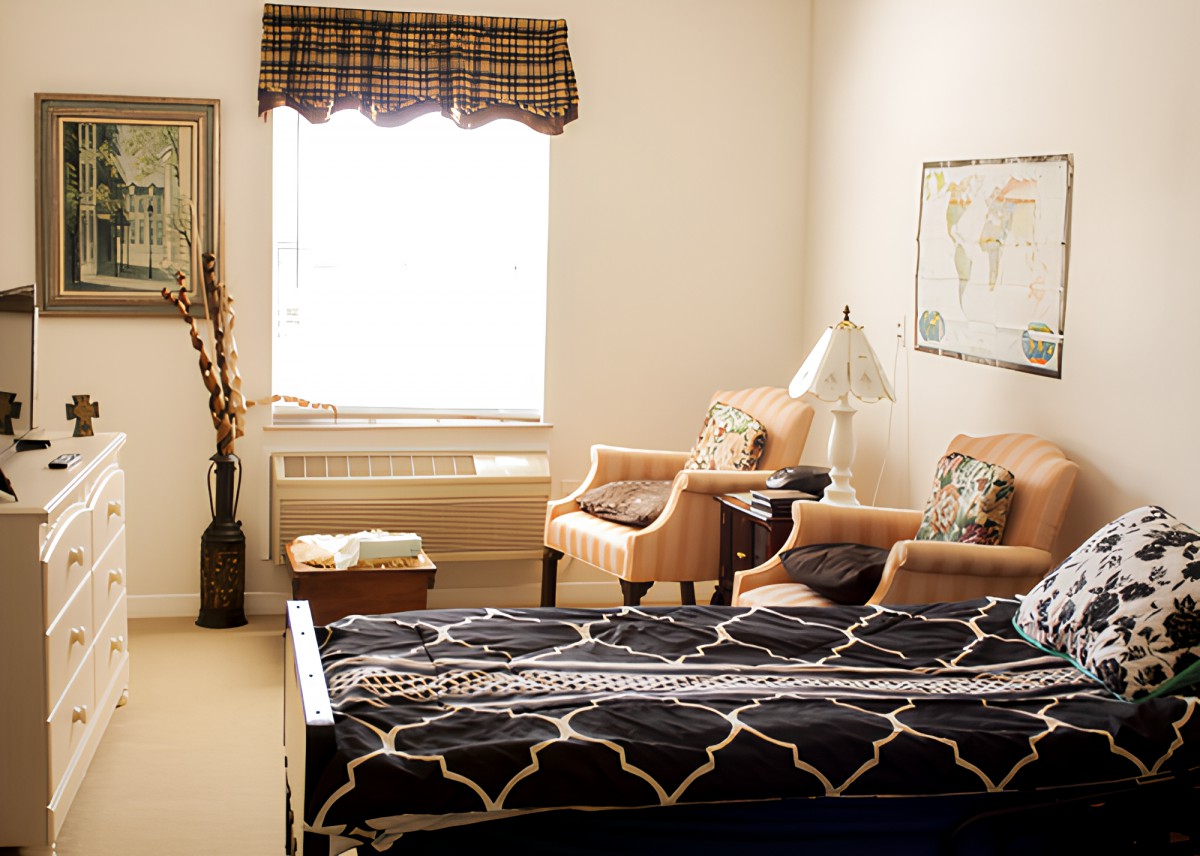 Cozy bedroom with a stylish bed, armchairs, and a large window.