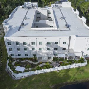 Aerial view of a modern white building surrounded by landscaped gardens.