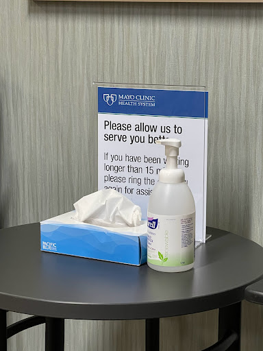 A customer service sign alongside hand sanitizer and tissues in a waiting area.