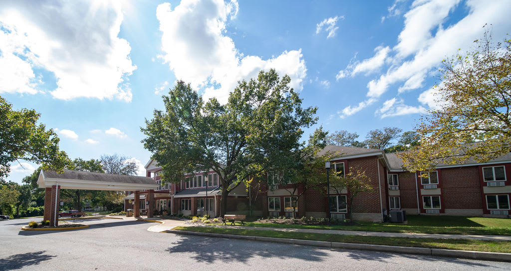 A sunny day with a building surrounded by trees under a blue sky.