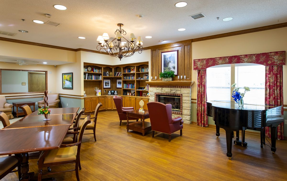 A cozy living room with a fireplace, bookshelves, and a chandelier.