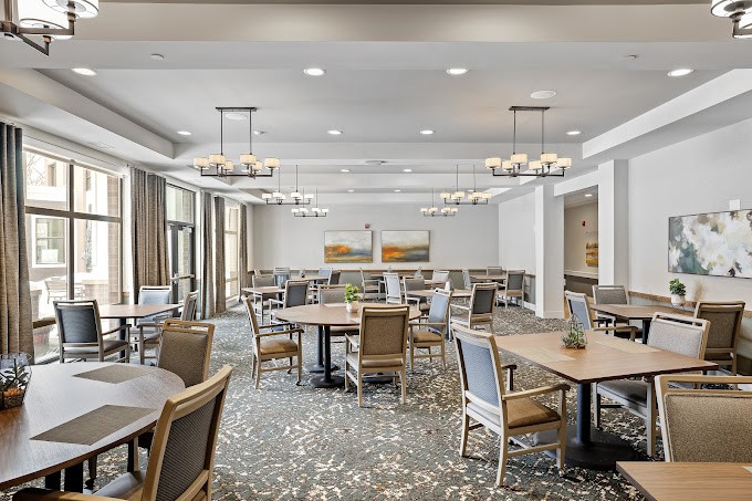 A modern dining room with neatly arranged tables and chairs, elegant lighting fixtures, and decorative wall art.