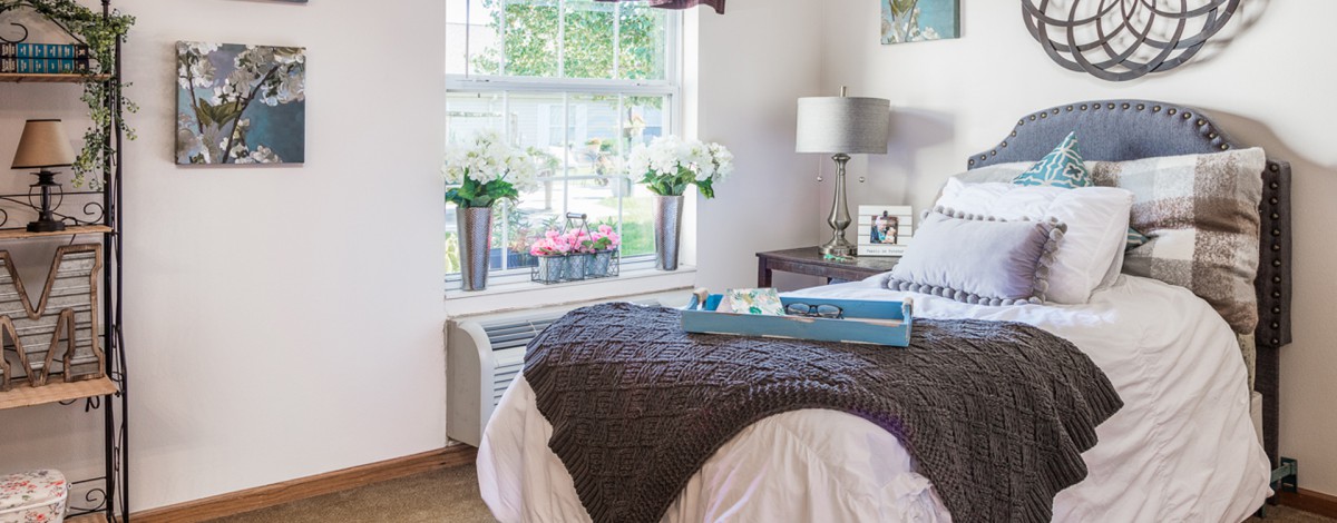 A cozy bedroom with fresh flowers and a neatly arranged bed.