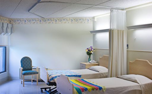 A serene patient room in a medical facility, featuring two beds and a floral arrangement.