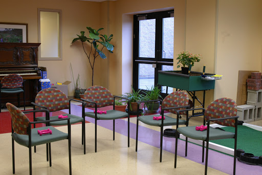A cozy waiting area featuring chairs neatly arranged, adorned with decorative napkins, and enhanced by indoor plants.