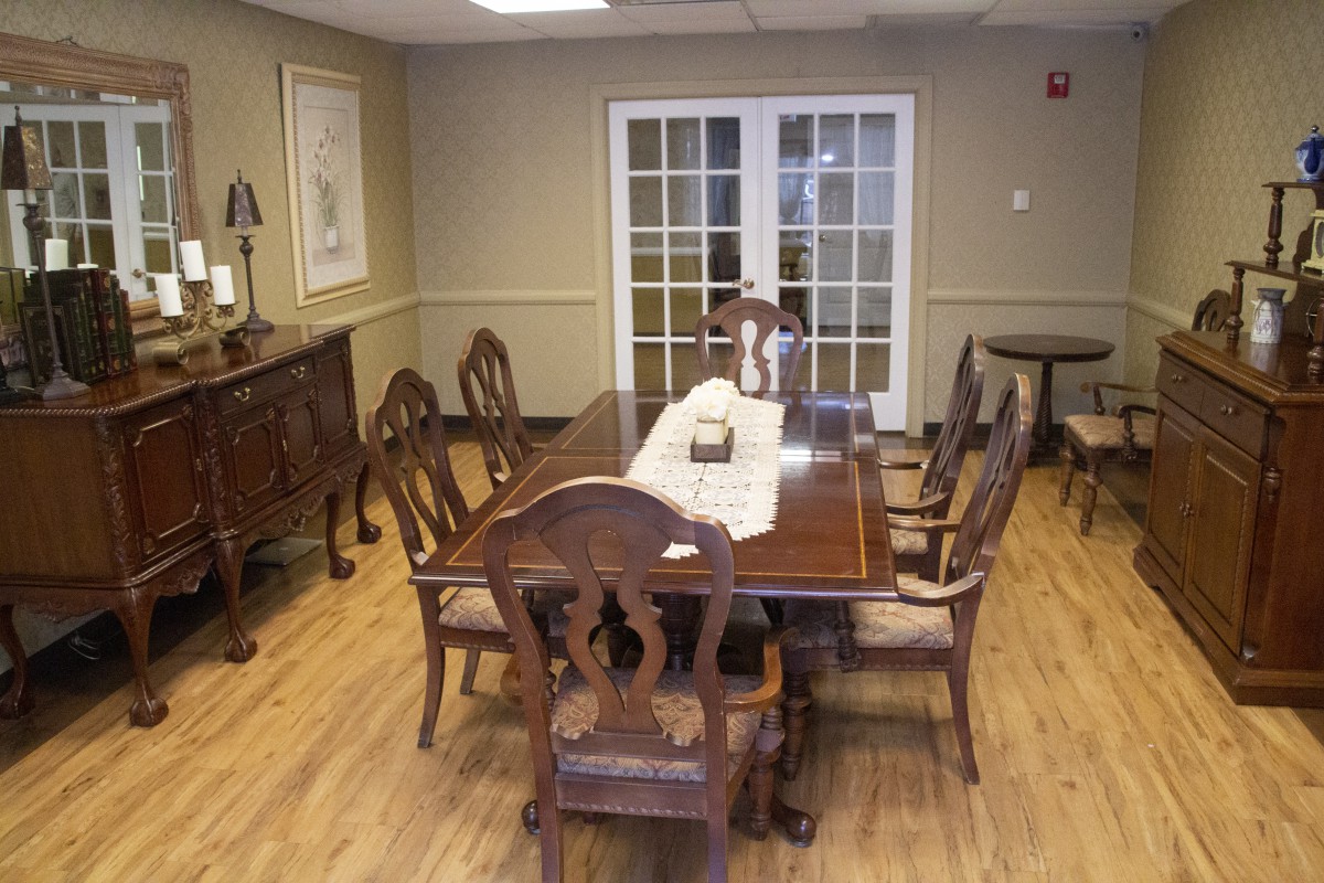 A classic dining room setting with a wooden table and chairs on a polished hardwood floor.