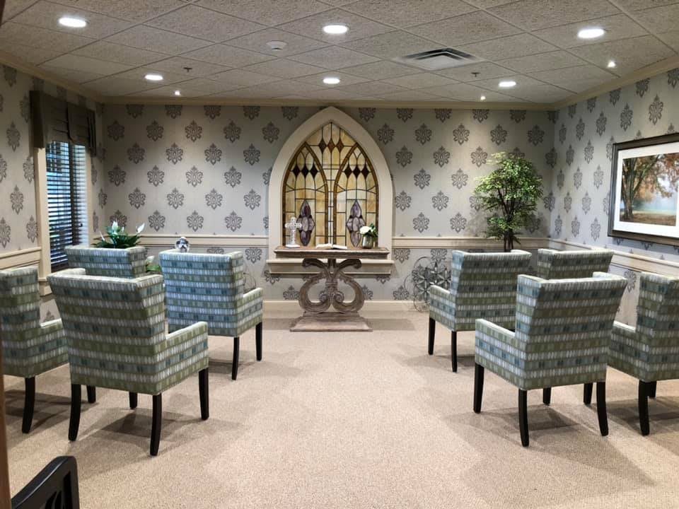 A serene waiting area with patterned chairs and decorative elements, including plants and a central table.